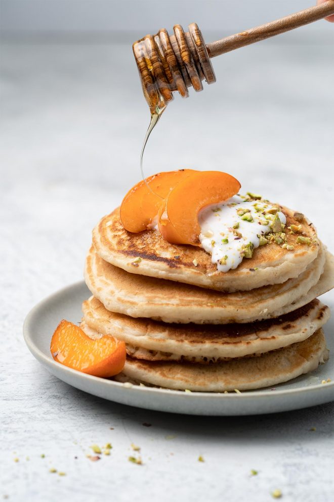 An image of a stack of pancakes with oranges and honey being drizzled on top as an example of a straight on camera angle.