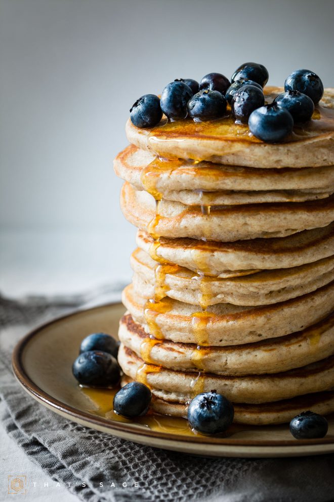 Stack of pancakes with syrup and blueberries photographed head-on, photograph by Lauren Caris Short of Food Photography Academy