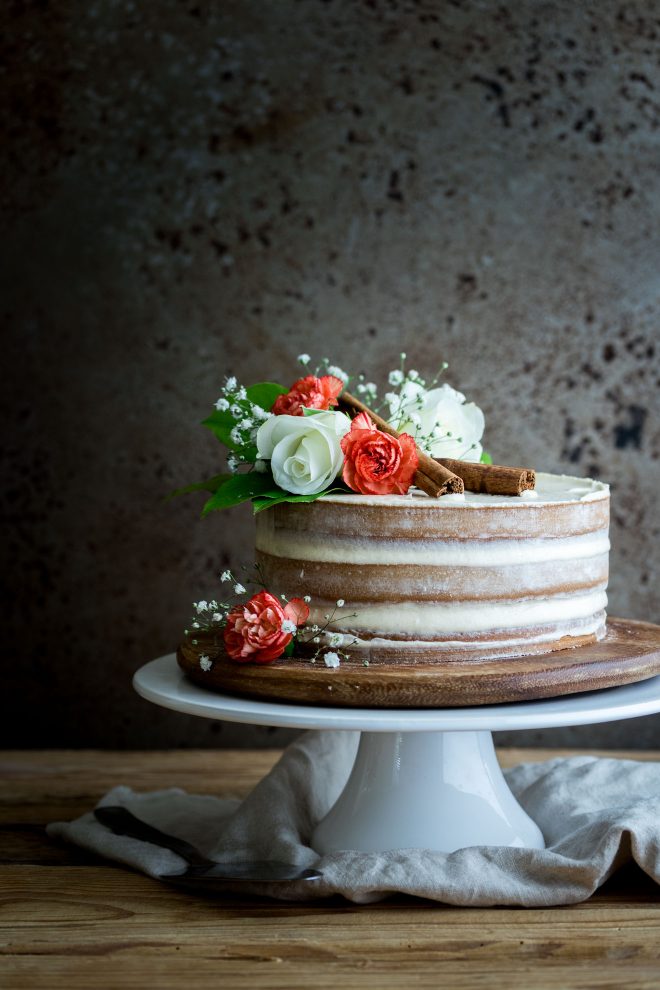 Naked cake with flowers and cinnamon sticks photographed head-on, photograph by Lauren Caris Short of Food Photography Academy