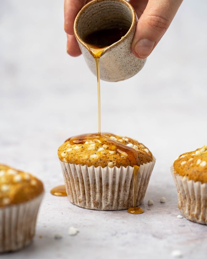 A hand pouring a ramekin of honey over a muffin. Photo by Lauren Caris Short of Food Photography Academy.