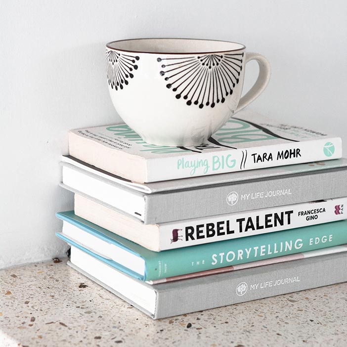 a stack of food photography books sit on a counter top with a coffee cup on top of them