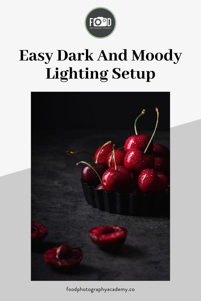 A small mountain of cherries rests in a tray with an easy dark and moody lighting setup by Lauren Short from Food Photography Academy. Image overlaid with text that reads Easy Dark and Moody Lighting Setup.